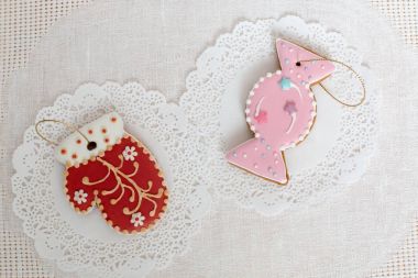 Şeker ve kırmızı mitten beyaz peçete arka plan üzerinde şeklinde iki gingerbread çerezleri. Üstten Görünüm, düz yatıyordu, kopya alanı. Kıvırcık Noel gingerbread ev yemekleri.