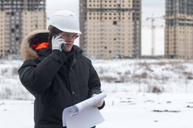 Mimar, mühendis, proje yöneticisi veya kıdemli mühendis inşaat gelince boş bir plan ile şehirde bina için Cb telefonda konuşan adam. Yumuşak odak.