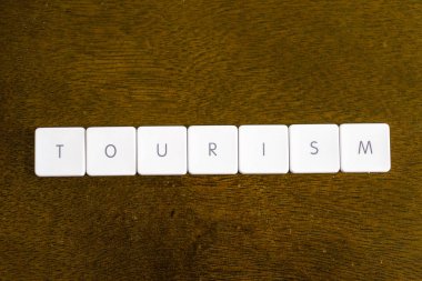 Plastik klavye alfabesi ile koyu arka plan üzerinde yazılı turizm kelime