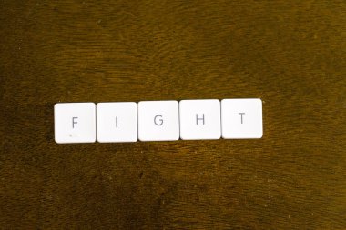 Plastik klavye alfabesi ile koyu arka plan üzerinde yazılı kelime mücadele