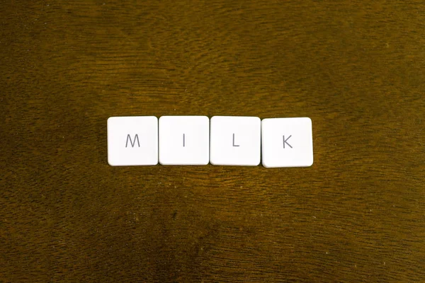 暗い背景でプラスチック製のキーボードは アルファベットで書かれた牛乳という言葉 — ストック写真