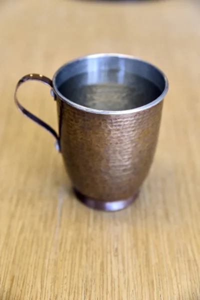 Canecas de cobre reais e puras de água na mesa no escritório — Fotografia de Stock