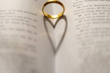 İncil 'in üzerinde, sayfasında kalp gölgesi olan bir alyans.