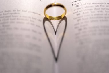 İncil 'in üzerinde, sayfasında kalp gölgesi olan bir alyans.