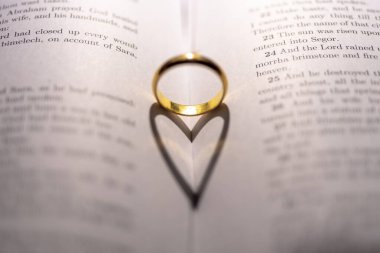İncil 'in üzerinde, sayfasında kalp gölgesi olan bir alyans.