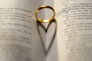 İncil 'in üzerinde, sayfasında kalp gölgesi olan bir alyans.
