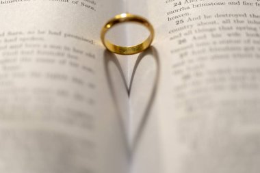 İncil 'in üzerinde, sayfasında kalp gölgesi olan bir alyans.