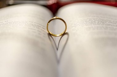 İncil 'in üzerinde, sayfasında kalp gölgesi olan bir alyans.