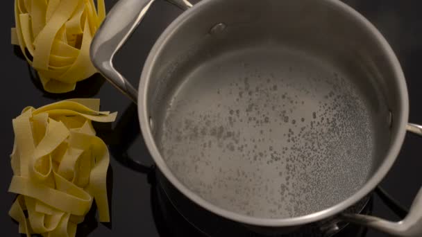 Boiling water in pan and nest pasta on electric stove — Stock Video