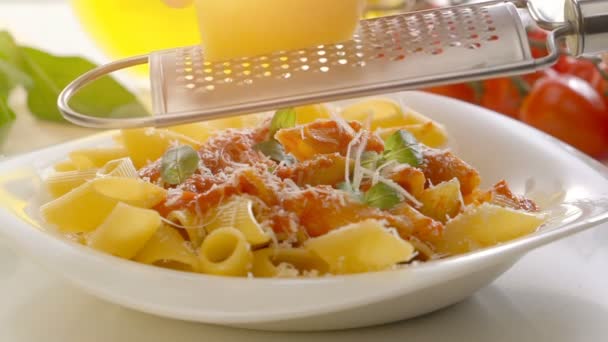 Mannelijke handen kaas raspen over penne pasta — Stockvideo