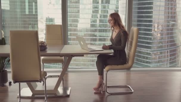 Mladá krásná žena sedí u okna a pracují na notebooku, Žena na pozadí města, — Stock video