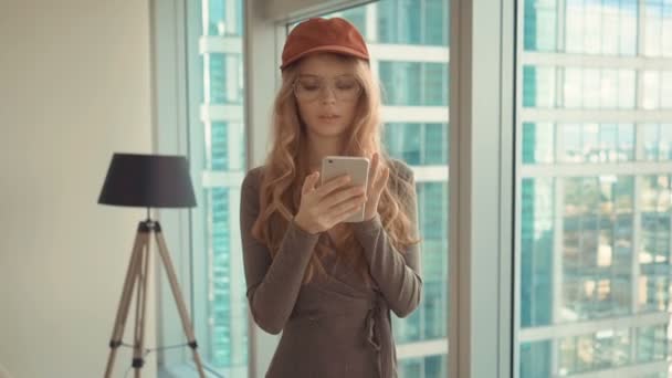 都市の背景に彼女の携帯電話から sms を送信するきれいな女性 — ストック動画