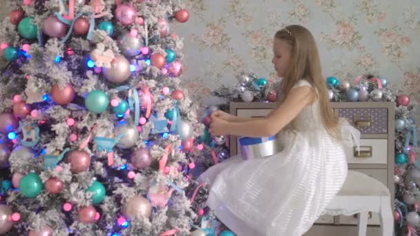 Linda niña en vestido blanco decorando el árbol de Navidad en casa — Vídeos de Stock