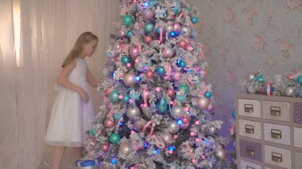 Linda niña en vestido blanco jugando con el árbol de Navidad en casa — Vídeos de Stock