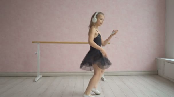 Šťastná holčička ve sluchátkách poslouchat hudbu z telefonu a tanec — Stock video
