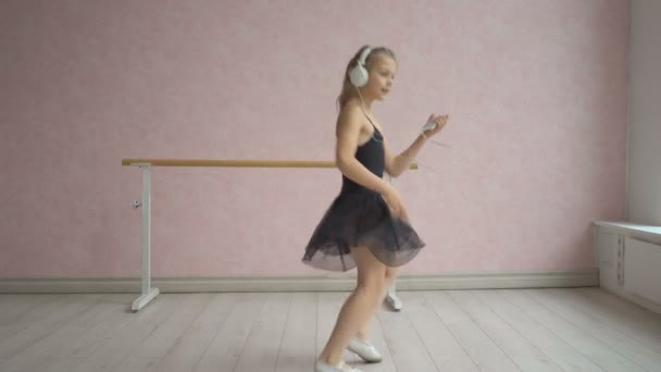 Lycklig liten flicka i hörlurar Lyssna på musik från smartphone och dans — Stockvideo