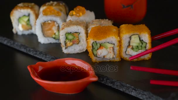 Palillos rojos tomando porción de rollo de sushi, comiendo rollo de sushi usando palillos — Vídeo de stock