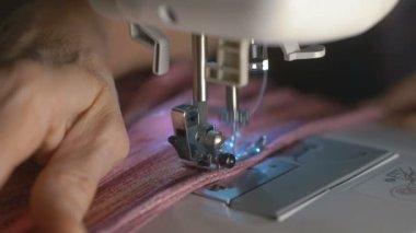 Yaşlı kadın eller Tekstil dikiş makinesi aracılığıyla ağır çekimde iterek.