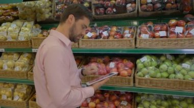 Erkekler süpermarkette meyve kontuarında tablet kullanma