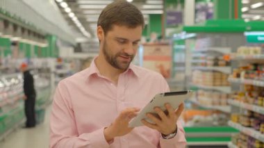Adam holding tablet hipermarket mağaza