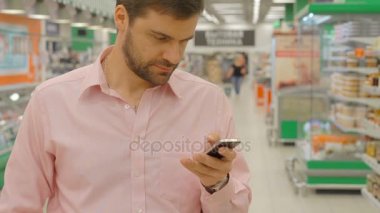 Alışveriş mağazası cep telefonu kullanan adam