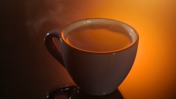 Schwarzer Tee in blauer Tasse mit Dampf darüber auf glänzendem Hintergrund, warme Abendstimmung, — Stockvideo