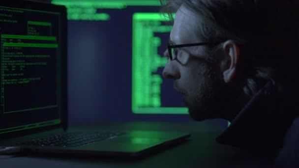 Manliga hacker eller programmerare som arbetar på en laptopi i en mörk kontorsrum. — Stockvideo