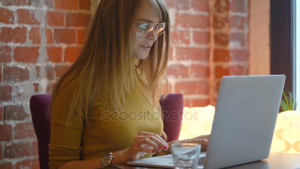 Schöne glückliche Frau, die während der Kaffeepause in der Cafébar am Laptop arbeitet — Stockvideo