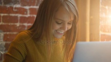 Güzel kız öğrenci tatlı gülümseme bir şey net-kitap, dizüstü bilgisayar üzerinde klavye ile. Işık parlaması