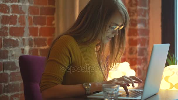 Ung kvinna skriver på laptop och leende på café. — Stockvideo