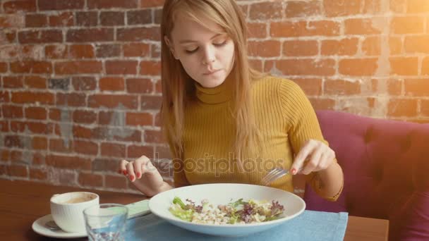 Young woman eating salad on lunch break in cafe and using her smart phone. — Stock Video