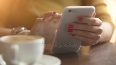 Onun cep telefonuna yazarak ince güzel manikürlü parmaklar, dumanı tüten fincan kahve, kafeterya masada oturan genç kızla.