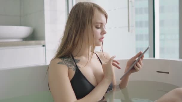 Mujer sexy joven con tatuaje usando tableta en el baño . — Vídeo de stock