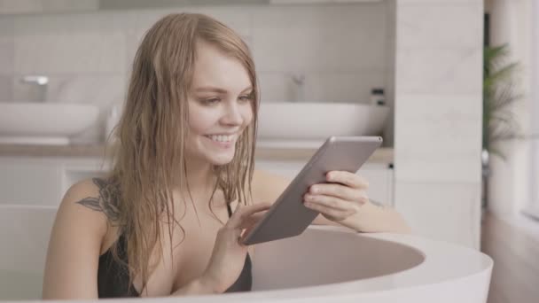 Ung sexig kvinna med hjälp av tablet PC i badet. — Stockvideo