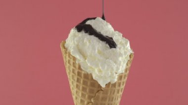 Vanilyalı dondurma waffle koni pembe bir arka plan üzerine çikolata sos ile
