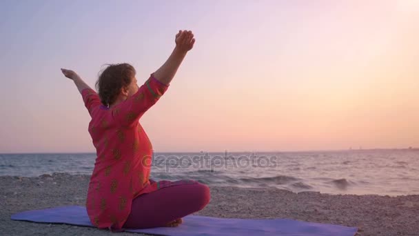 Жінка, що медитує в позі лотоса на сході сонця. Ранкова медитація. Концепція медитації йоги. Молода жінка практикує йогу на відкритому повітрі — стокове відео