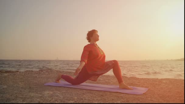 Yoga al atardecer en la playa. mujer haciendo yoga, realizando asana — Vídeos de Stock