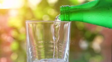 Yeşil şişe ve bulanık bokeh arka plan üzerine su dökerek