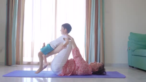 Мама занимается фитнесом со своим маленьким мальчиком дома . — стоковое видео
