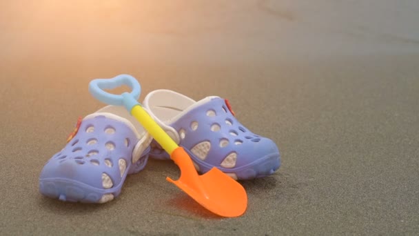 Kids crocs on wet sandy beach over sea background — Stock Video