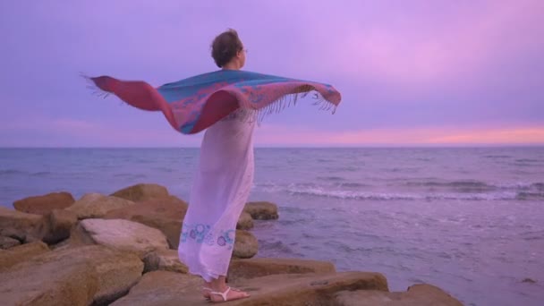 Vrouw in een witte jurk met kleurrijke cohandkerchief aan de oever van de zee — Stockvideo