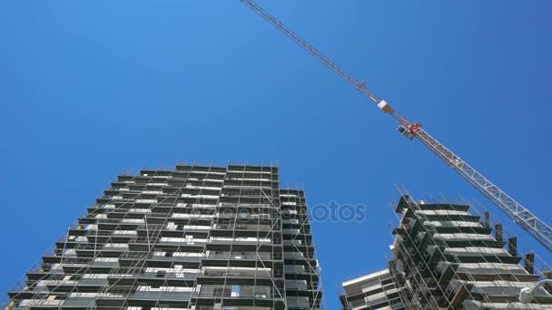 Building crane and building under construction against blue sky — Stock Video