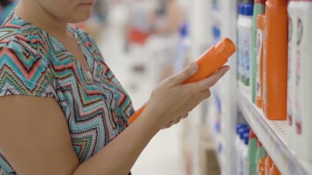 Woman using her mobile to choose ihousehold products in supermarket — Stock Video