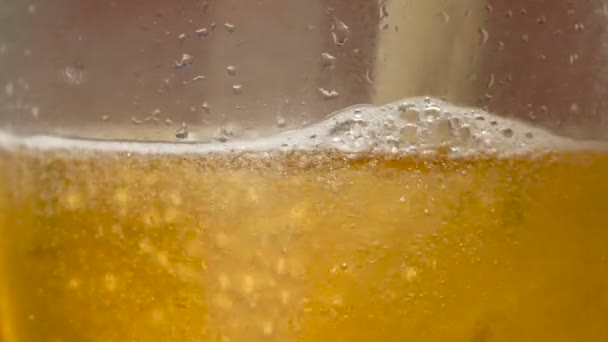 Burbujas de cerveza de primer plano extremo en un vaso mientras se vierte — Vídeo de stock