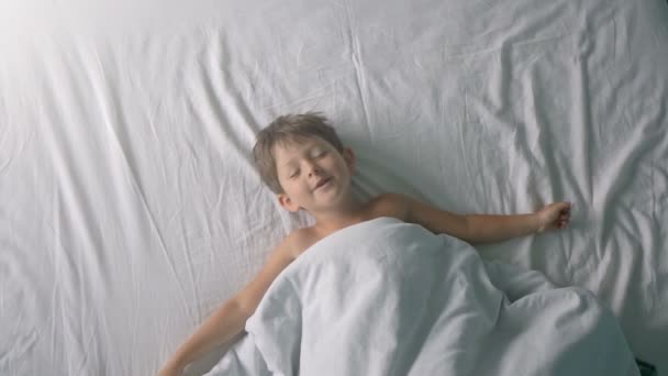 Kleine jongen die zich uitstrekt in bed na wake up — Stockvideo