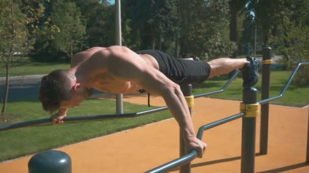Atleta muscular haciendo ejercicio en un gimnasio al aire libre — Vídeos de Stock