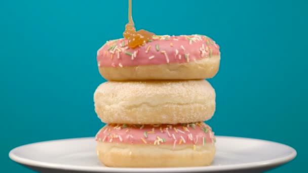 Três deliciosos donuts de morango rosa rotativos com cobertura de caramelo — Vídeo de Stock