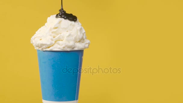 Вращение мягкого ванильного мороженого в синей бумажной чашке с шоколадным соусом — стоковое видео