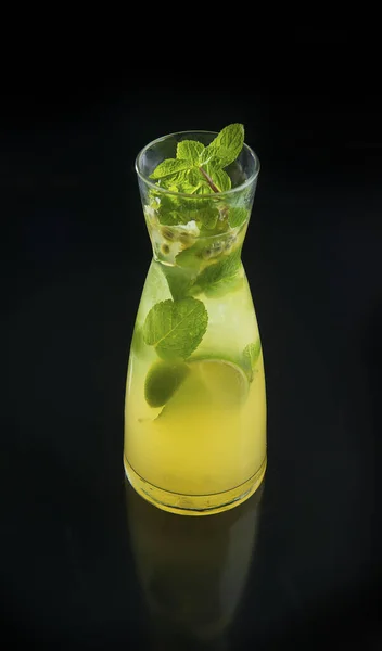 Fresh citrus lemonade with lemon, lime, and mint in glass jug on the black background — Stockfoto