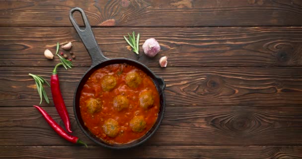 Cuisson des boulettes de viande avec sauce tomate dans une poêle noire. Pose plate, vue du dessus avec espace de copie — Video